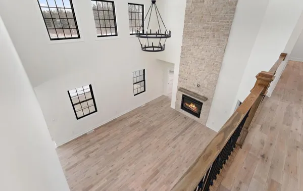 a view of an empty room with wooden floor and a fireplace