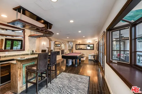 a large kitchen with stainless steel appliances granite countertop a large stove top oven a sink dishwasher a dining table and chairs with wooden floor