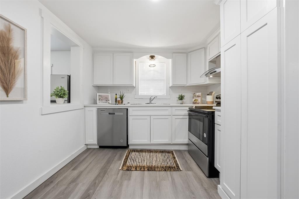 1116 Houston Street Waco, TX 76704 - Photo 6 of 16 Kitchen featuring white cabinets, light countertops, stainless steel appliances, light wood-style flooring, and tasteful backsplash