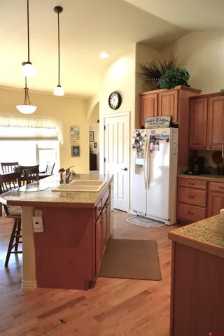 a kitchen with stainless steel appliances granite countertop a stove a sink dishwasher and a refrigerator with wooden floor