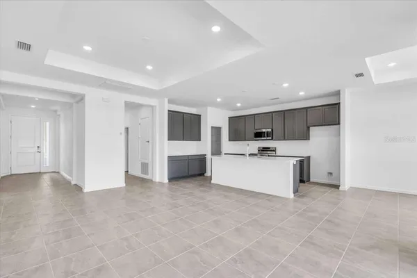 a large white kitchen with kitchen island a sink a stove a microwave and cabinets