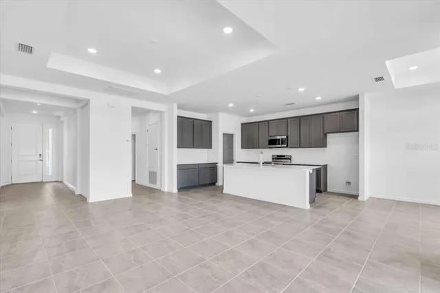 a large white kitchen with kitchen island a sink a stove a microwave and cabinets