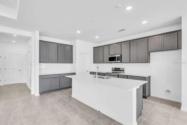 a kitchen with a sink a stove top oven a refrigerator and white cabinets
