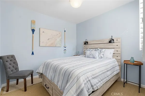 a bedroom with a bed a chair and painting on the wall