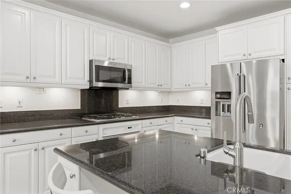 a kitchen with granite countertop a sink stove and refrigerator