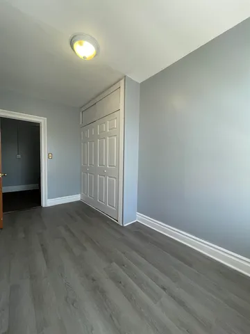 a view of an empty room with wooden floor and closet