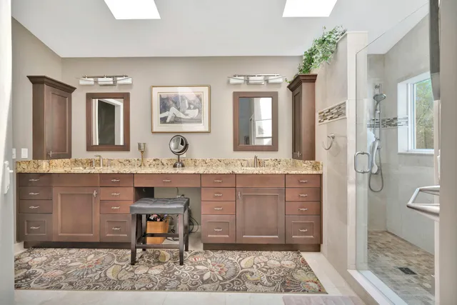 a bathroom with a granite countertop sink a mirror and a shower