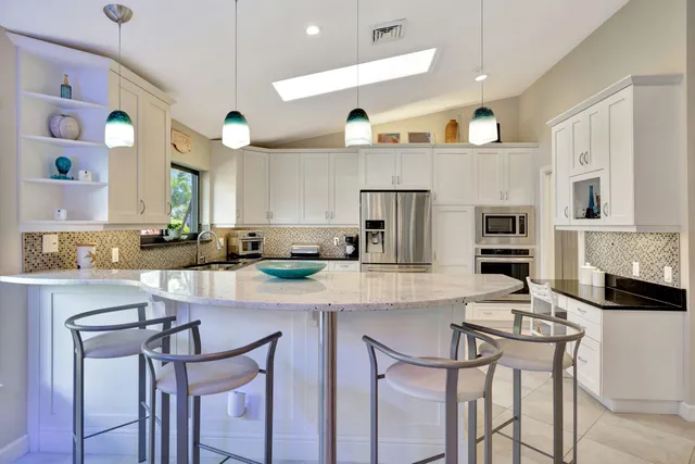 a kitchen with stainless steel appliances kitchen island granite countertop a table chairs sink and cabinets
