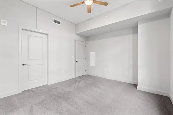 an empty room with a chandelier fan and closet area