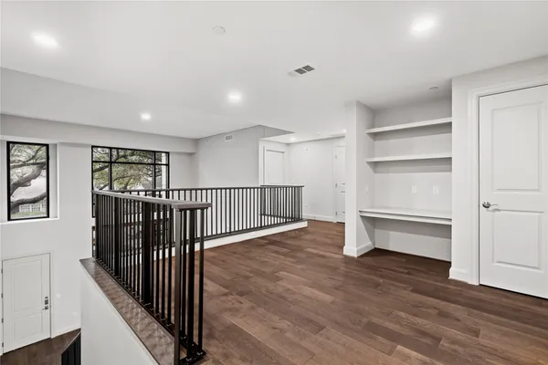 a view of a hallway with stairs and wooden floor