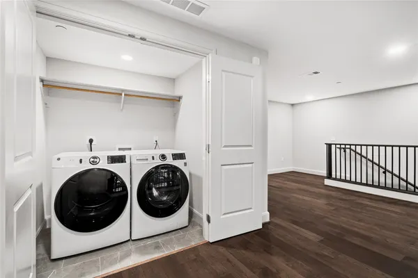 a utility room with wooden floor sink washer and dryer