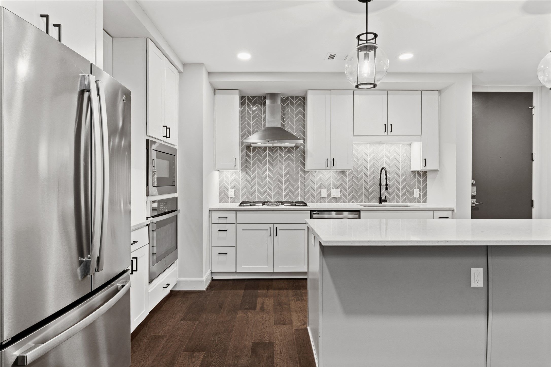 2511 Willowick Road, Unit 117 Houston, TX 77027 - Photo 8 of 43 a kitchen with stainless steel appliances granite countertop a refrigerator a sink dishwasher a stove and white cabinets with wooden floor