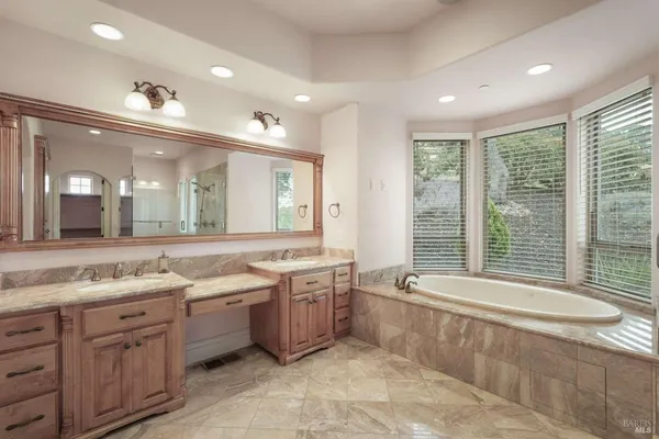 a spacious bathroom with a double vanity sink a large mirror and a bathtub