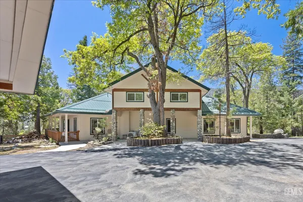 a front view of a house with a garden and tree