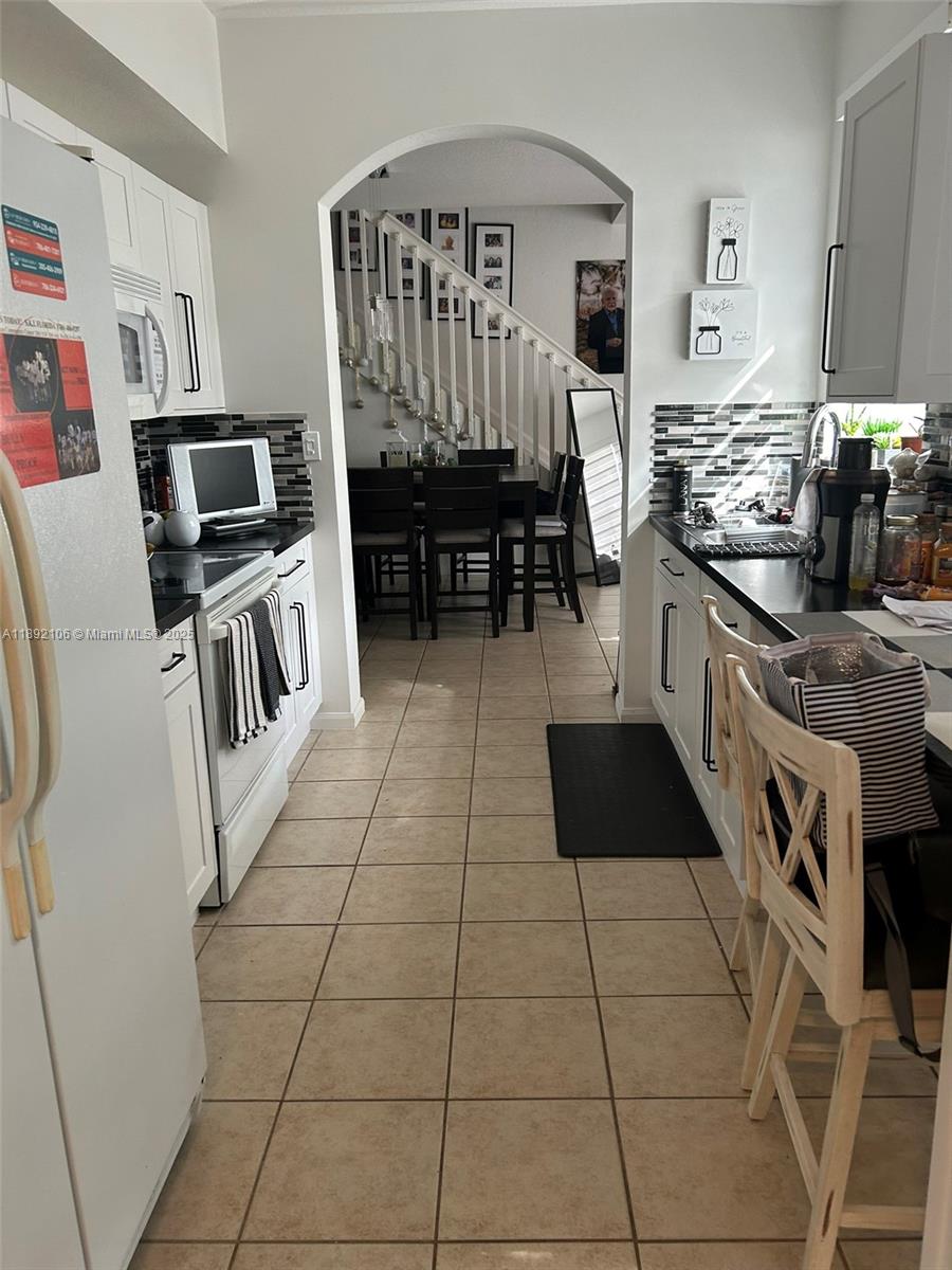18730 Southwest 25th Court, Unit 18730 Miramar, FL 33029 - Photo 8 of 30 a kitchen with granite countertop a stove a sink and a microwave
