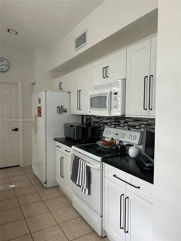 a kitchen with white cabinets a sink stove and refrigerator