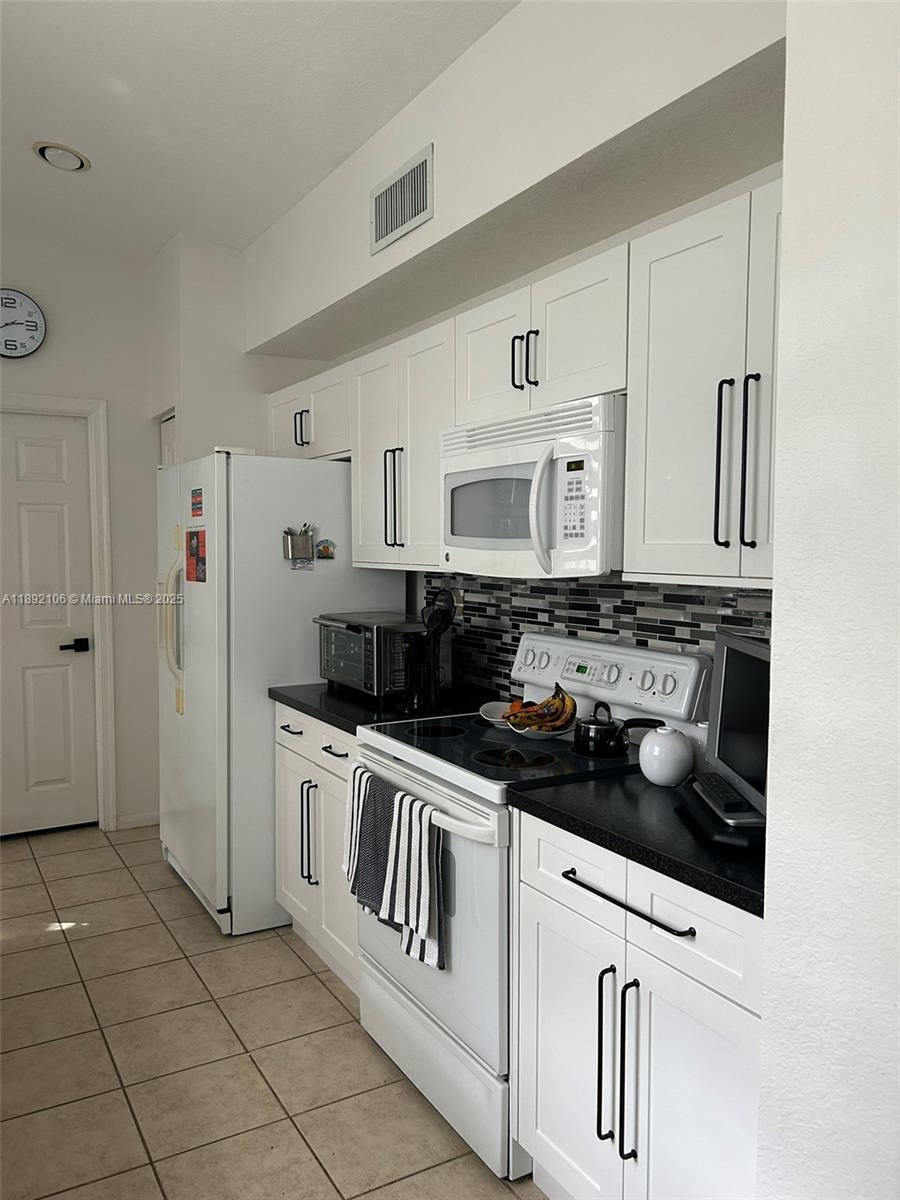 18730 Southwest 25th Court, Unit 18730 Miramar, FL 33029 - Photo 9 of 30 a kitchen with white cabinets a sink stove and refrigerator