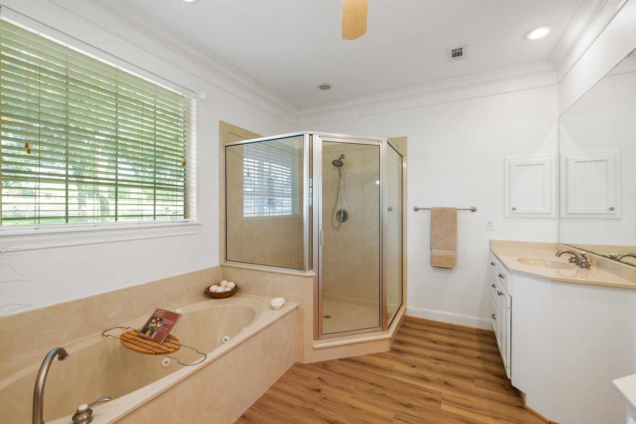 34310 High Point Drive Magnolia, TX 77355 - Photo 17 of 48 This bathroom features a spacious layout with a large jetted soaking tub, a separate glass-enclosed shower, and a dual-sink vanity. Natural light streams in through a window with blinds, highlighting the neutral color palette for a modern, inviting atmosphere.