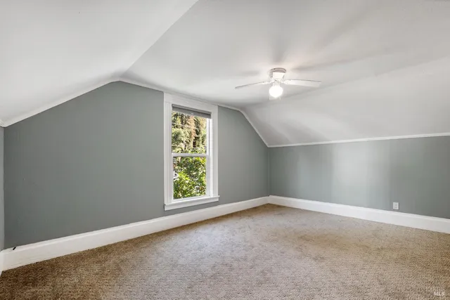 an empty room with windows and ceiling fan