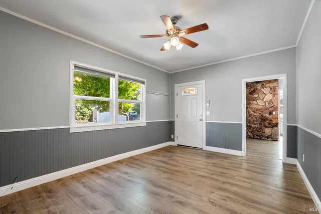 a view of empty room with wooden floor and fan