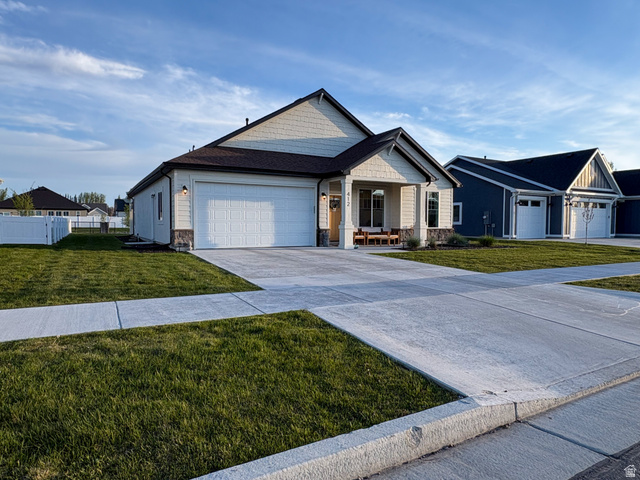 412 West 3025th Street South Logan, UT 84321 - Photo 3 of 34 View of front facade featuring a garage, a porch, stone siding, and concrete driveway