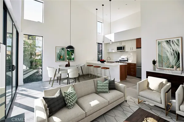 a living room with furniture kitchen view and a large window