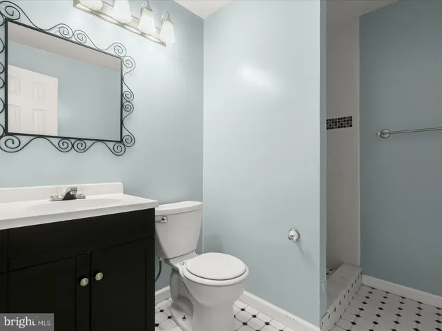 a bathroom with a toilet sink vanity and mirror