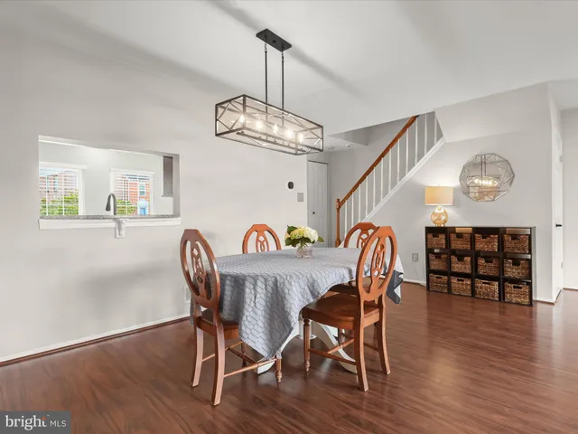 a dining room with wooden floor a chandelier a wooden table and chairs