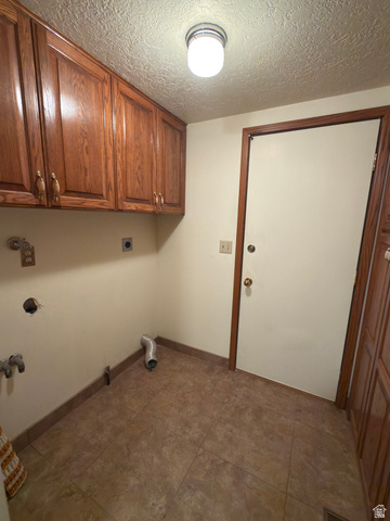 1164 East Mountain Road Logan, UT 84321 - Photo 26 of 45 Utility space featuring wood-finish cabinetry, tile flooring, a flush-mount ceiling light, and a solid core door with wood-finish trim