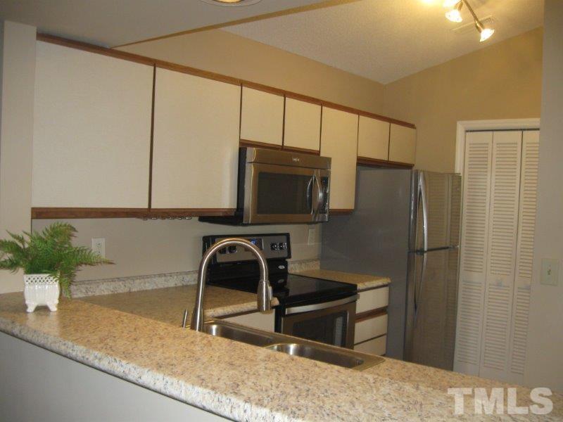 6111 Sunpointe Drive, Unit 201 Raleigh, NC 27606 - Photo 11 of 17 a kitchen with a refrigerator a sink and a stove top oven