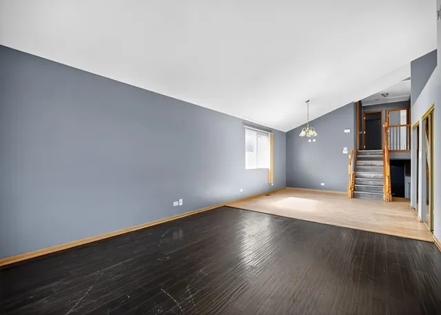 a view of an empty room with wooden floor and stairs