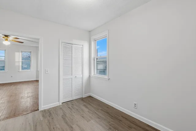an empty room with wooden floor and windows