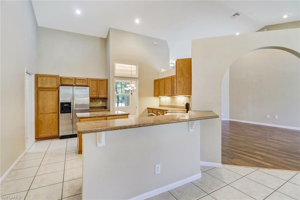 6564 Chestnut Circle Naples, FL 34109 - Photo 11 of 27 a large kitchen with stainless steel appliances a large counter top a stove and a refrigerator