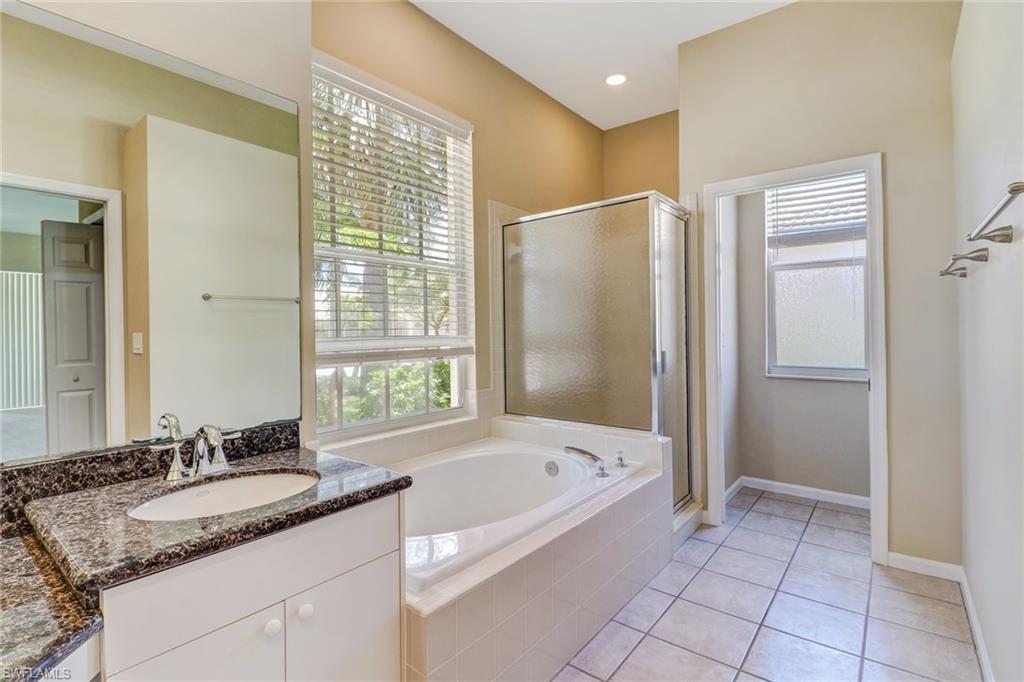6564 Chestnut Circle Naples, FL 34109 - Photo 15 of 27 a bathroom with a granite countertop bathtub a sink and a mirror