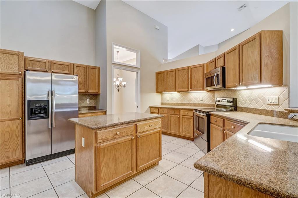 6564 Chestnut Circle Naples, FL 34109 - Photo 9 of 27 a kitchen with stainless steel appliances granite countertop a refrigerator and a stove top oven