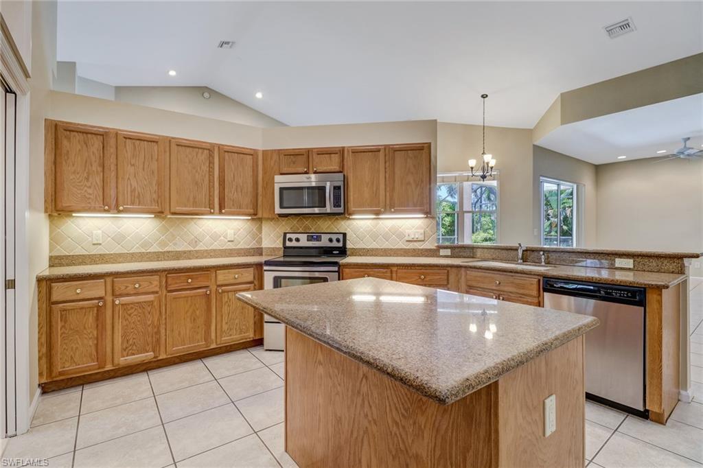 6564 Chestnut Circle Naples, FL 34109 - Photo 10 of 27 a kitchen with kitchen island granite countertop a stove sink and cabinets