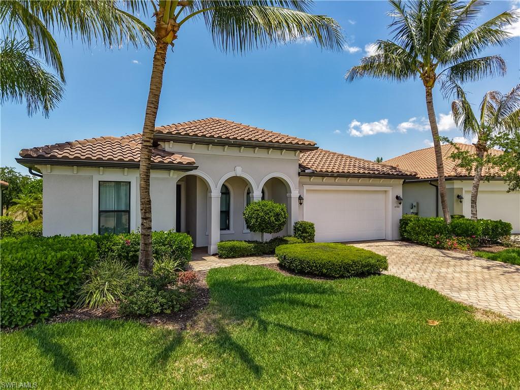 Mediterranean / spanish home featuring an attached garage, stucco siding, decorative driveway, a front lawn, and a tiled roof