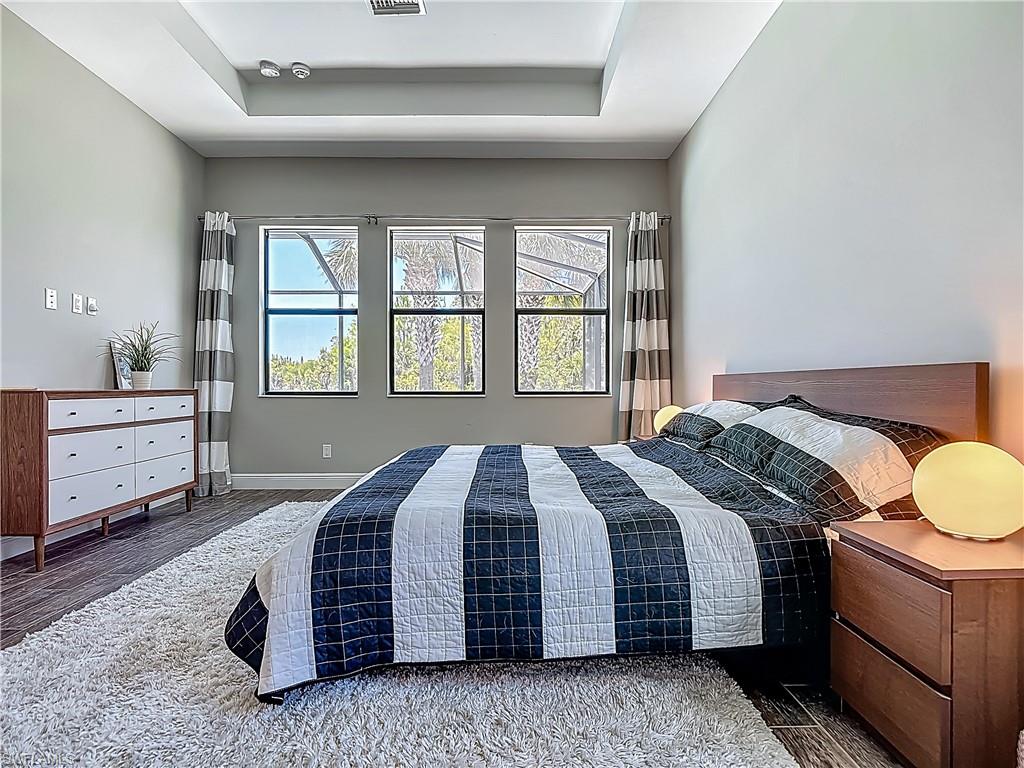 4524 Tamarind Way Naples, FL 34119 - Photo 26 of 50 Bedroom featuring a tray ceiling, wood finished floors, and baseboards