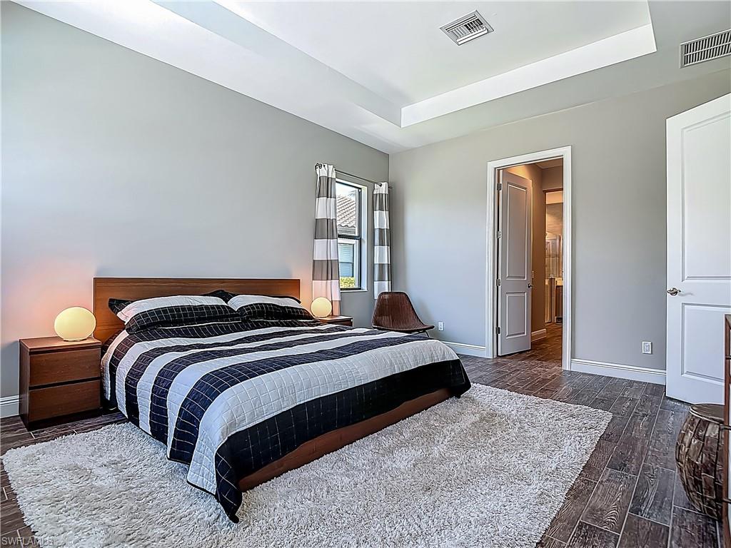 4524 Tamarind Way Naples, FL 34119 - Photo 29 of 50 Bedroom with a raised ceiling, baseboards, and dark wood-type flooring