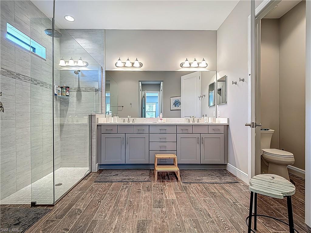 4524 Tamarind Way Naples, FL 34119 - Photo 31 of 50 Full bathroom featuring wood finished floors, double vanity, a shower stall, healthy amount of natural light, and recessed lighting