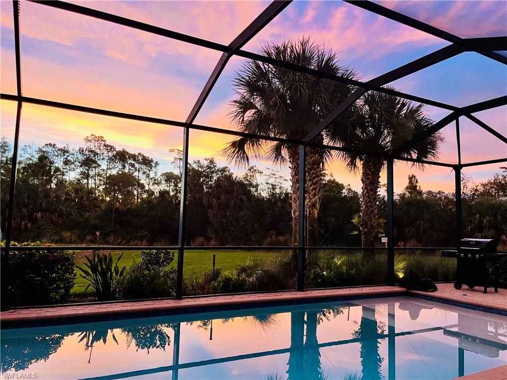 4524 Tamarind Way Naples, FL 34119 - Photo 45 of 50 Pool at dusk with glass enclosure, an outdoor pool, a grill, and a patio