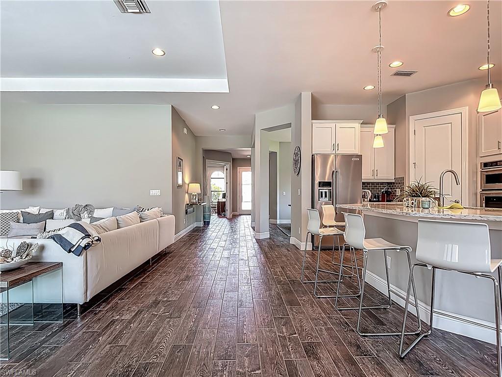 4524 Tamarind Way Naples, FL 34119 - Photo 49 of 50 Kitchen with a breakfast bar, dark wood-type flooring, open floor plan, high end fridge, and white cabinets