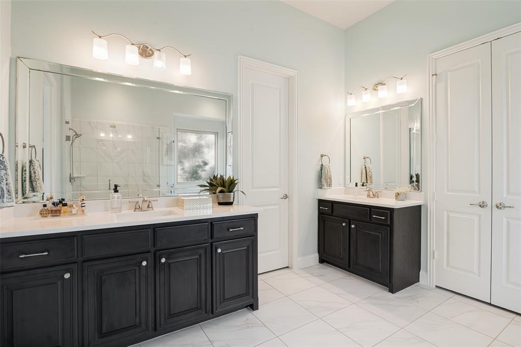388 Bethany Road Sunnyvale, TX 75182 - Photo 18 of 40 Dual vanity bathroom featuring a large framed mirror, square tile flooring, light blue wall paint, dark wood-finish cabinetry, and white countertops