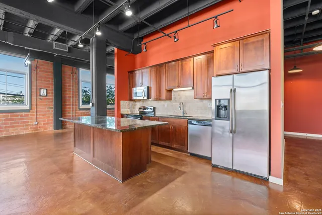 a kitchen with stainless steel appliances granite countertop a refrigerator and a stove