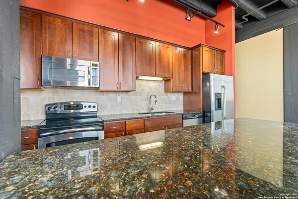 a kitchen with stainless steel appliances granite countertop a refrigerator and a stove top oven