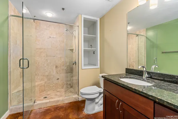 a bathroom with a granite countertop sink a toilet and shower