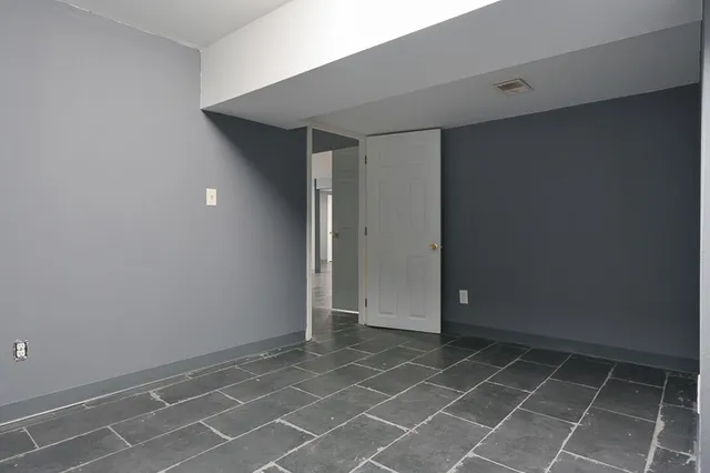 a view of an empty room with closet and a window