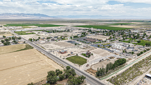 84 White Sage Avenue, Unit 2 Delta, UT 84624 - Photo 6 of 18 Expansive rural landscape featuring a paved road, agricultural fields, scattered residential structures, and distant mountains under a partially cloudy sky