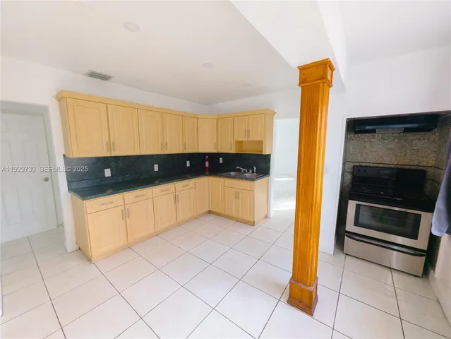 a kitchen with granite countertop a sink a stove and cabinets