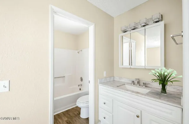 a bathroom with a granite countertop sink a toilet and a bathtub